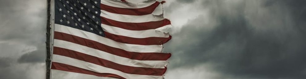 tattered American flag against a stormy sky